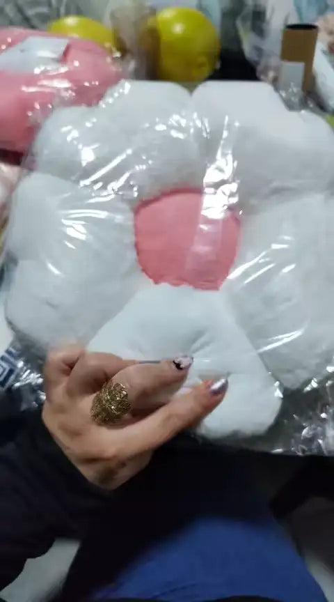 Coussin en peluche blanc et rose en forme de fleur.
