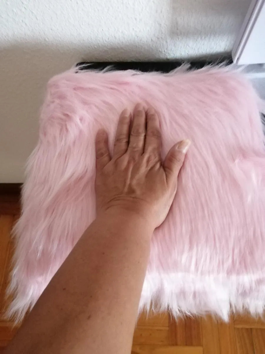 Une dame qui met la main sur un coussin en laine rose