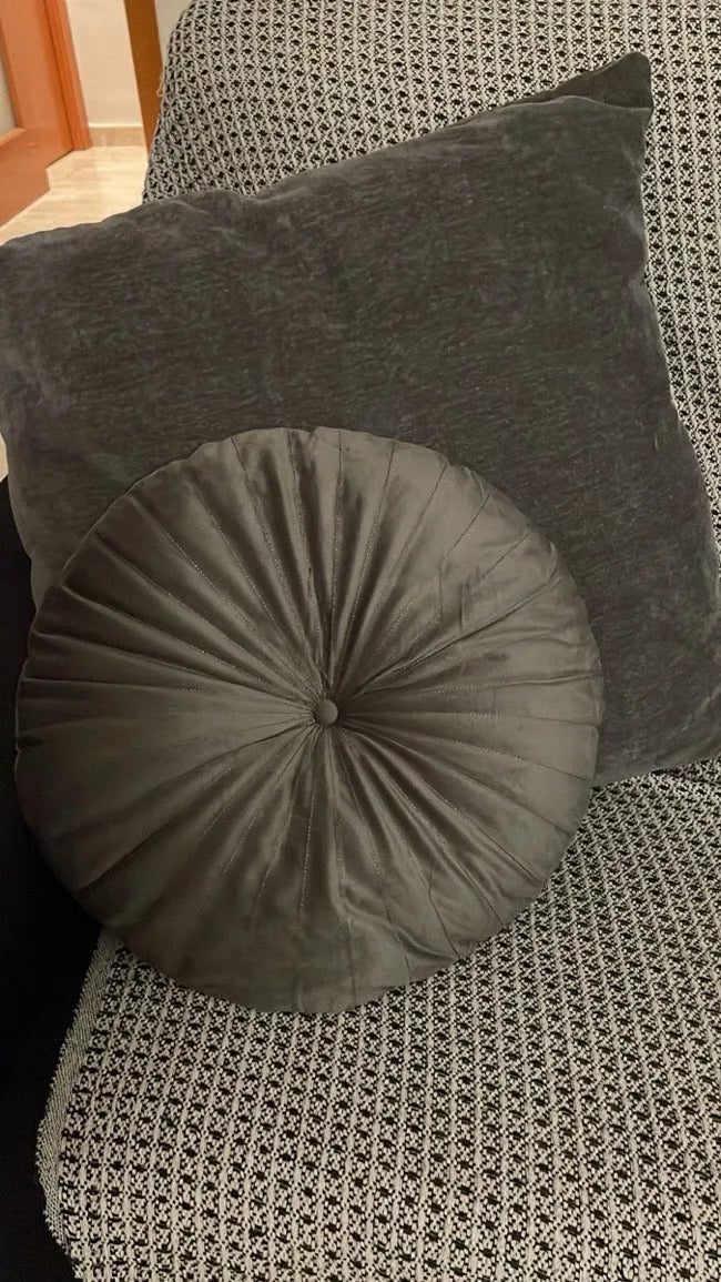 Un coussin rond gris sur un fauteuil